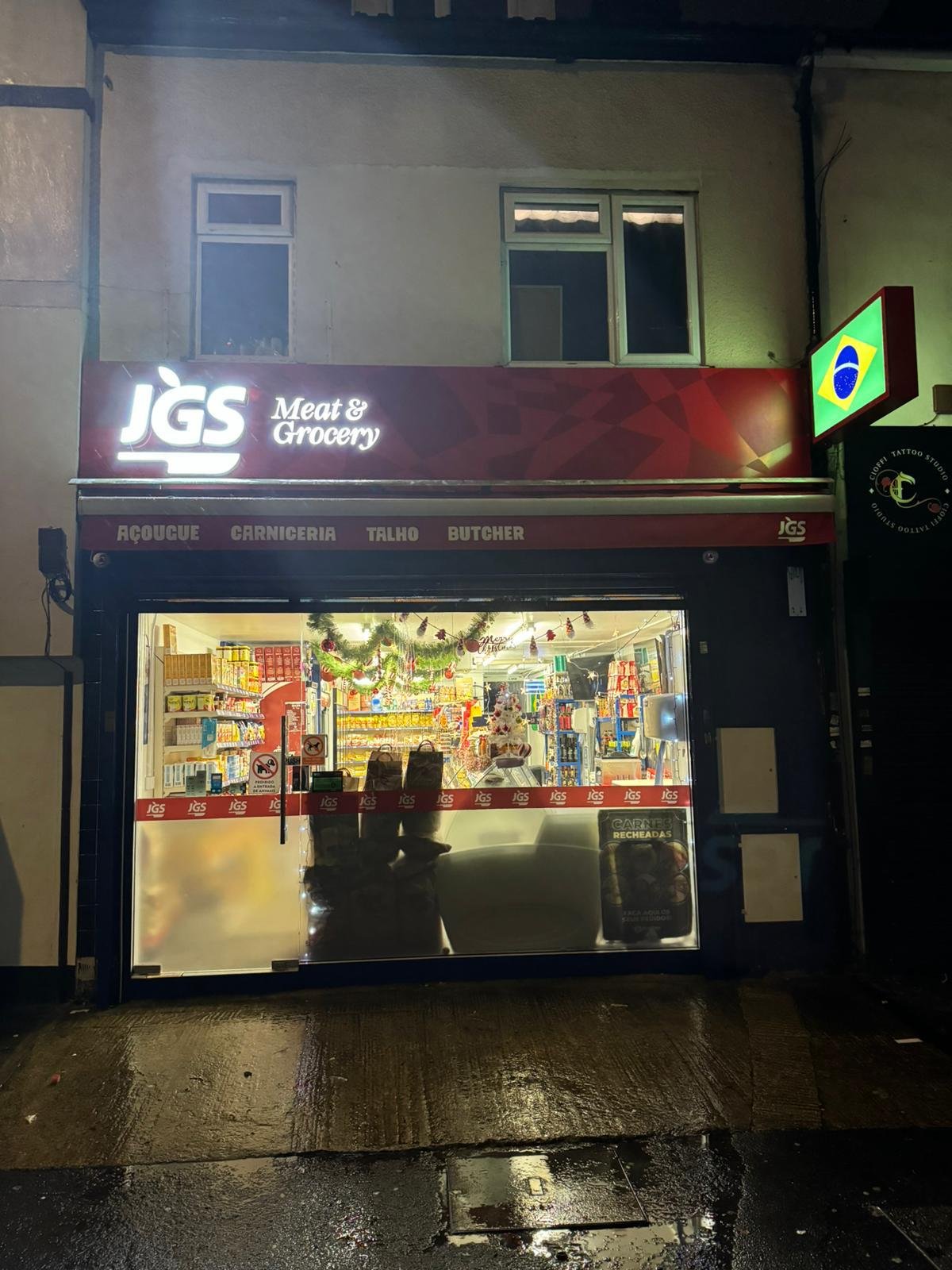 A photograph of the JGS Meat and Grocery storefront lit at night