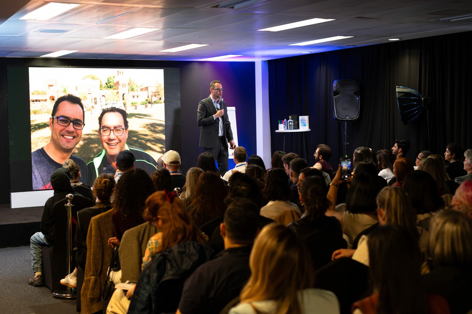 The audience watching two speakers appear on the main screen