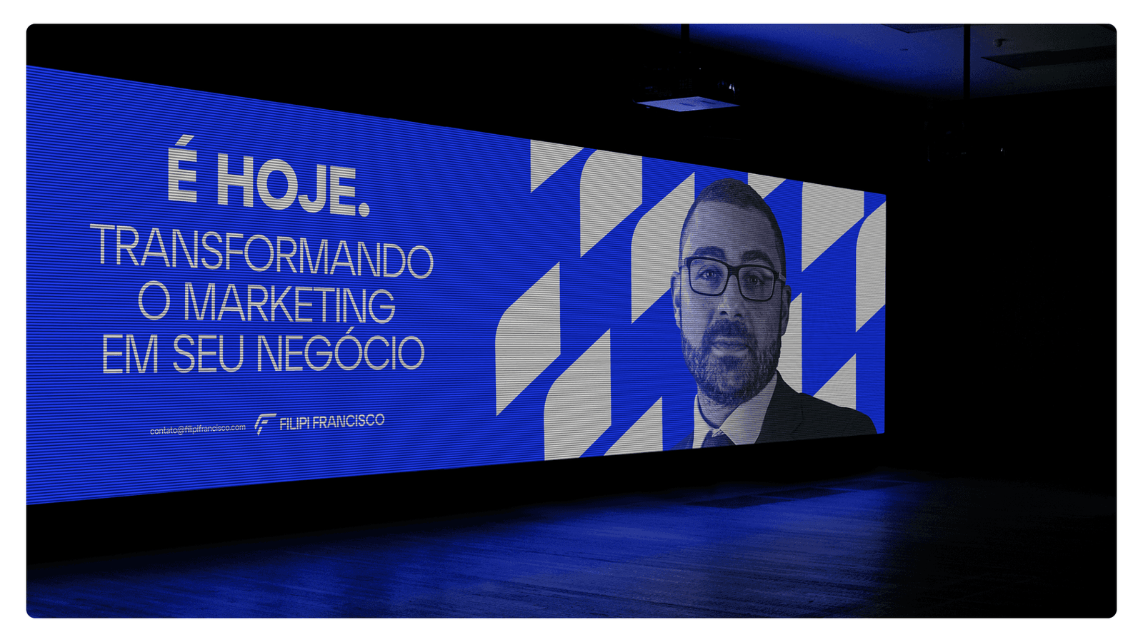 A stage LED wall reading E HOJE, transforming marketing into your business, with a speaker pictured alongside