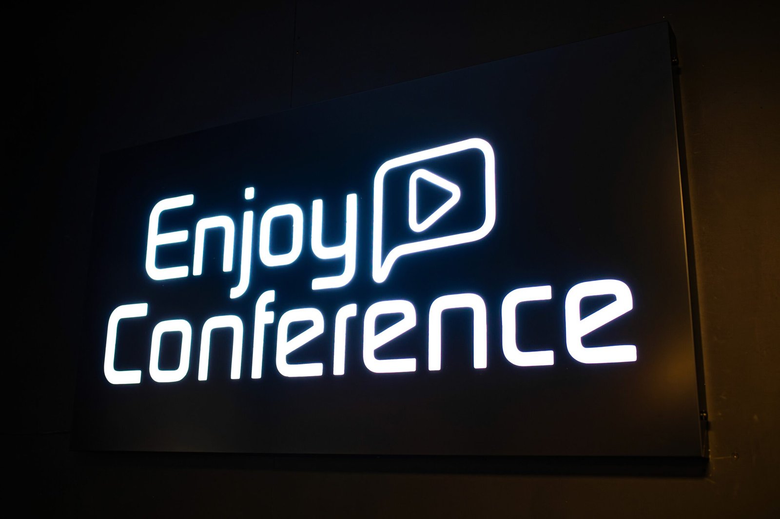 The Enjoy Conference logo glowing on a dark screen